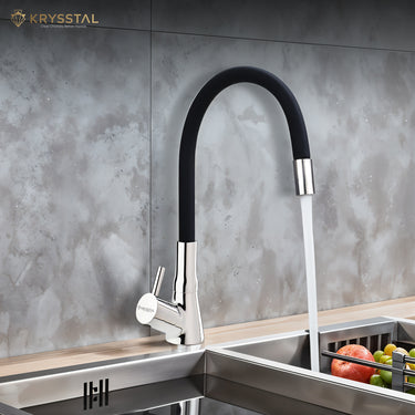 A black mounted kitchen sink tap with a silicone spout, featuring a black flexible hose and a silver-colored faucet head with water flowing from it mounted on a wooden slab.