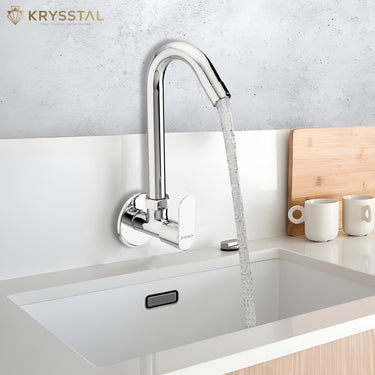 A modern chrome swan-neck faucet pouring water into the drain of a white sink basin.