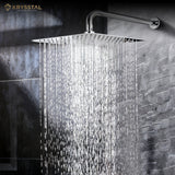 Square stainless steel overhead rain shower with wall-mounted arm releasing water fitted on a tile wall.
