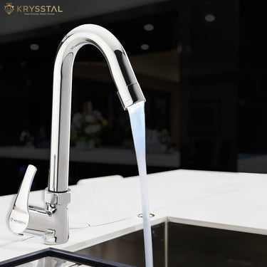 A polished chrome kitchen faucet with a gentle gooseneck curve, with water running into the sink on a black faded background.