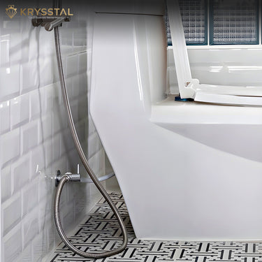 A hanging view of flexible tube shower beside the white toilet sheet fitted on the glossy tiles
