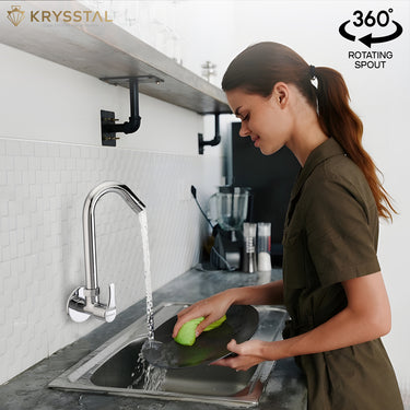 A woman is washing dishes under a wall-mounted kitchen sink tap with a rotating spout.