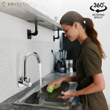 A woman is washing dishes under a wall-mounted kitchen sink tap with a rotating spout.