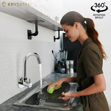 A woman is washing dishes under a wall-mounted kitchen sink tap with a rotating spout.