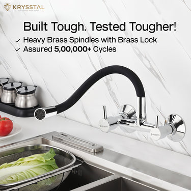 Dual-control chrome kitchen mixer tap with a flexible spout "Built Tough & Tested Tougher" tag, mounted on the wall above the sink.