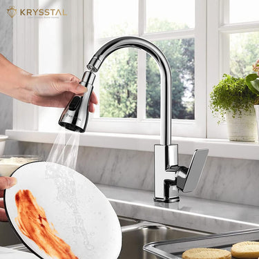 A silver-colored faucet aerator with hand-held pulling features is shows while washing the plate. in a kitchen setting.
