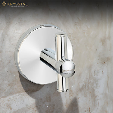 A silver stainless steel robe hook with a round backplate and a vertical crossbar fitted on a grey wall.