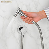 Handheld shower head with flexible hose held by a hand on a marble background, featuring the Krysstal brand.