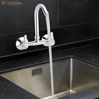 Chrome-finish kitchen mixer tap with flowing water, featuring a high-arc spout and twin handles fitted on a black tile.