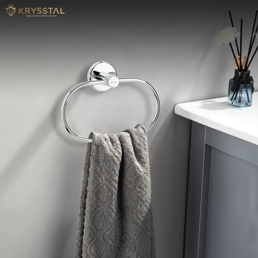 The towel hanging on a silver stainless steel towel ring with a round wall-mounted base beside the flower glass on the white table.