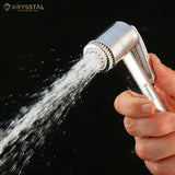 A hand-held silver health faucet with a flowing water spray on a black background.