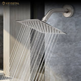 Square stainless steel overhead rain shower with wall-mounted arm releasing water fitted on a tile wall.