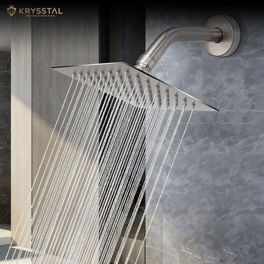 Square stainless steel overhead rain shower with wall-mounted arm releasing water fitted on a tile wall.