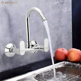 A silver kitchen sink mixer tap with a water flowing into the sink with high arch and two handles & put 2 apples beside the sink, fitted on a white background.