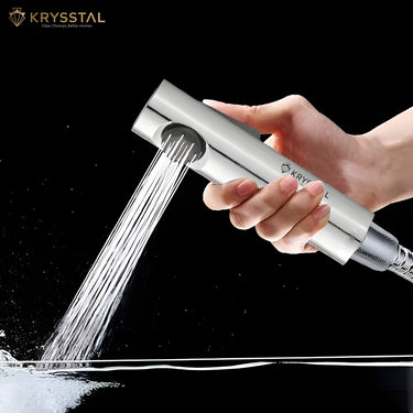 Handheld shower head with water flowing, held by a hand against a black background, Krysstal brand visible.