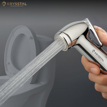 Hand holding a Krysstal shower head with water flowing towards a toilet.