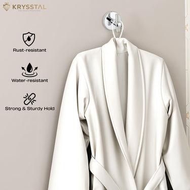 A stainless steel wall hook in silver with a round base and vertical crossbar with a bathrobe displayed on a grey backdrop.