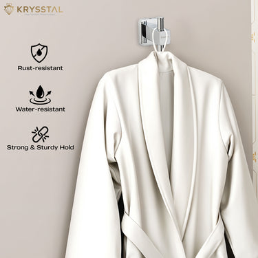 A stainless steel square-shaped robe hook with a hanging bathrobe on a vertical rod extends from the square fitted on a grey wall background