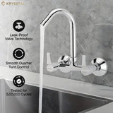 The metallic kitchen faucet with dual handles and its 3 features & high-arc design fitted on a white & grey textured background.