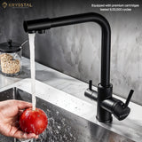 Black kitchen faucet with water flowing into a sink, shows while washing the hand-held an apple on a grey background.