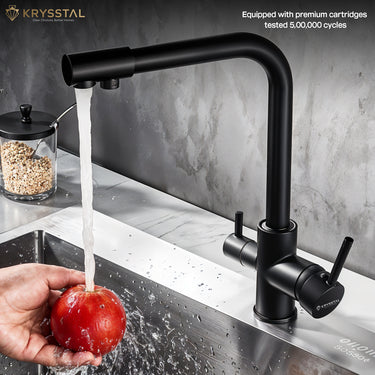 Black kitchen faucet with water flowing into a sink, shows while washing the hand-held an apple on a grey background.