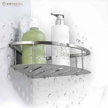 A silver SS corner shelf tray with a triangular shape fitted on a white wall with the holding of a green & white bottle dispenser.