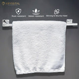 The white towel hanging on a silver stainless steel towel rod shows 3 benefits on top on a grey wall and is placed against a black background.