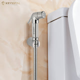 Silver health faucet with flexible hose mounted on marble wall beside white toilet seat.