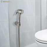 Diamond brass health faucet with shower hose mounted on a tiled bathroom wall beside a toilet seat.