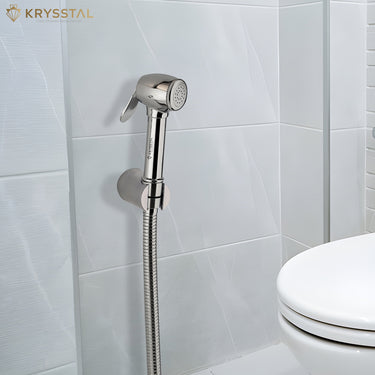 Diamond brass health faucet with shower hose mounted on a tiled bathroom wall beside a toilet seat.