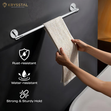 A hand-held peach-colored towel draped over a polished stainless steel rod with round ends on a black wall with its features on the right side.