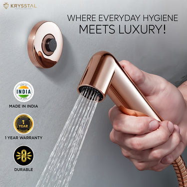 Rose gold colored handheld health faucet with a left-side manufacturing detail and wall hook.