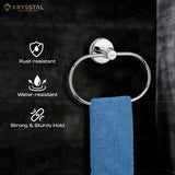 The blue towel hanging on a silver stainless steel towel ring with a round wall-mounted base with 3 written features on the left side on a black tile wall.