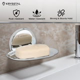 A wall-mounted silver soap dish holding soap, reflecting on the holder, fitted on a brown textured wall, with its features on top & a white washbasin at the bottom.