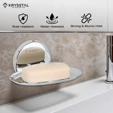 A wall-mounted silver soap dish holding soap, reflecting on the holder, fitted on a brown textured wall, with its features on top & a white washbasin at the bottom.