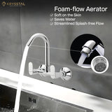A silver "Foam flow aerator" featured kitchen sink mixer tap fitted on a grey wall with a flowing water into the sink