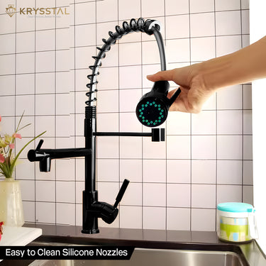 Black kitchen faucet with a hand holding a nozzle fitted on a kitchen sink against a tiled wall background