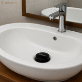 White sink with chrome faucet reflecting its mirror and Krysstal branding in a bathroom setting.