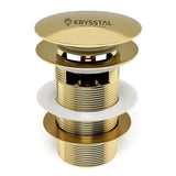 Gold bathroom drain stopper with Krysstal logo on a white background
